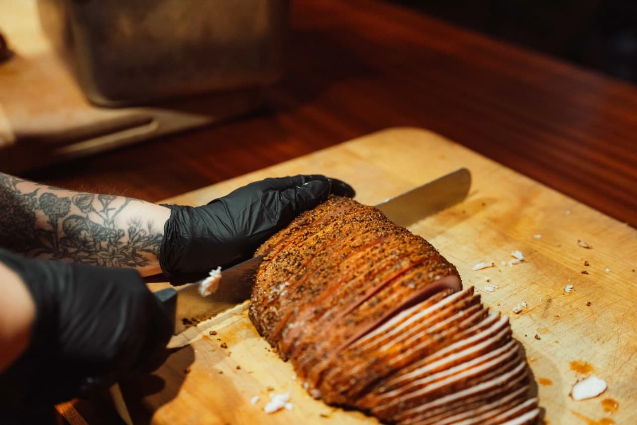 Cook hand-slicing seasoned brisket on a wooden cutting board