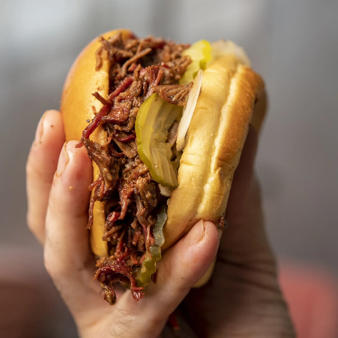Close-up of a pulled meat sandwich with pickles