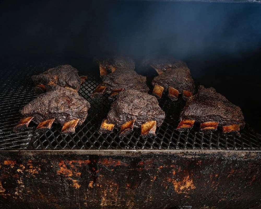 Smoked ribs on a barbecue grill in a dark outdoor setting